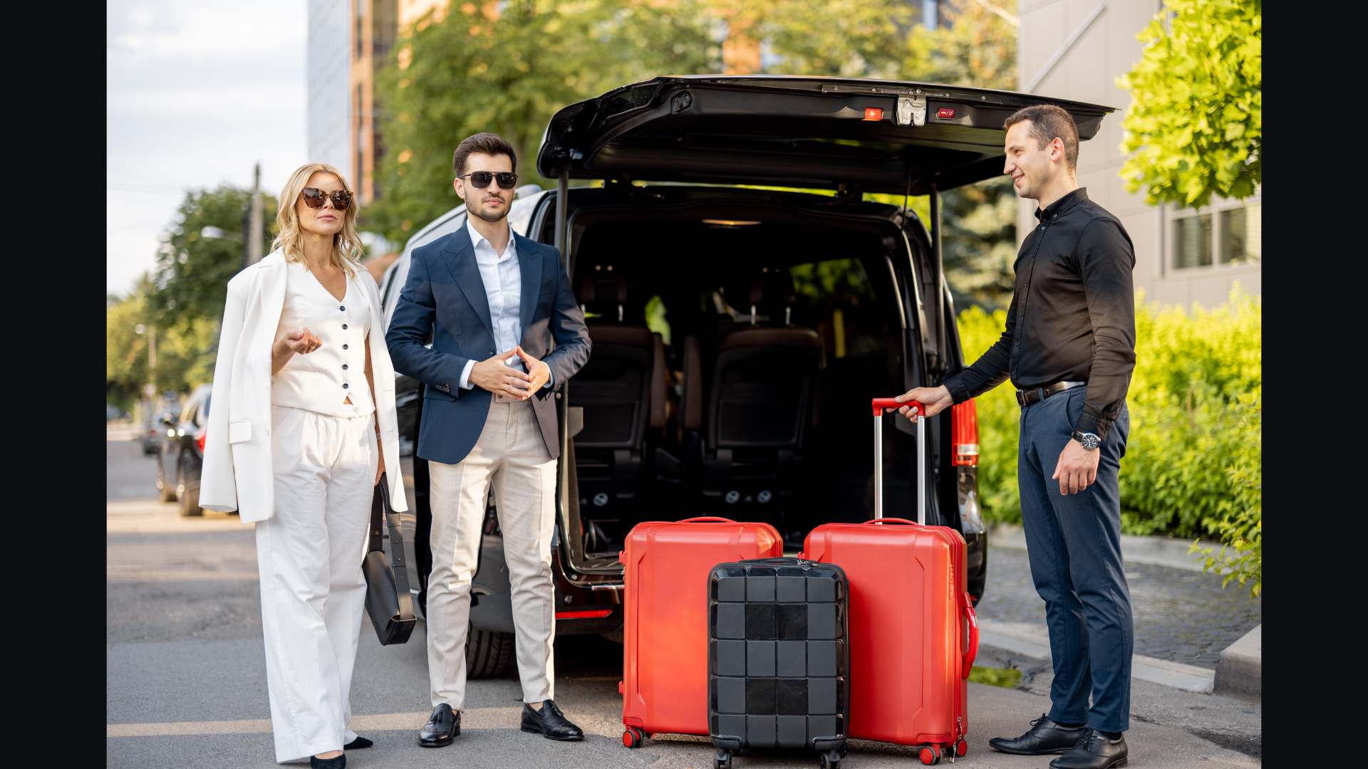 Luna chauffeur loading red travel cases into the rear of a Mercedes-Benz Sprinter while a couple waits at a hotel curb